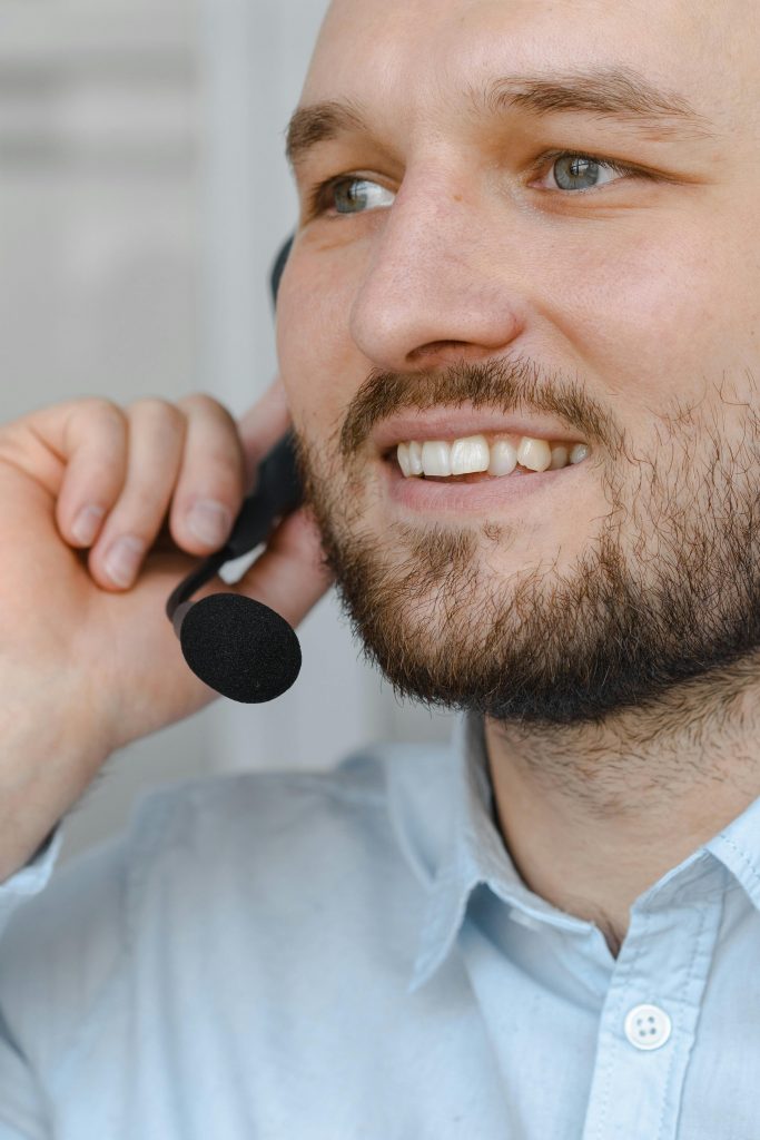 Close-up of a bearded man talking into a headset, representing friendly customer service.